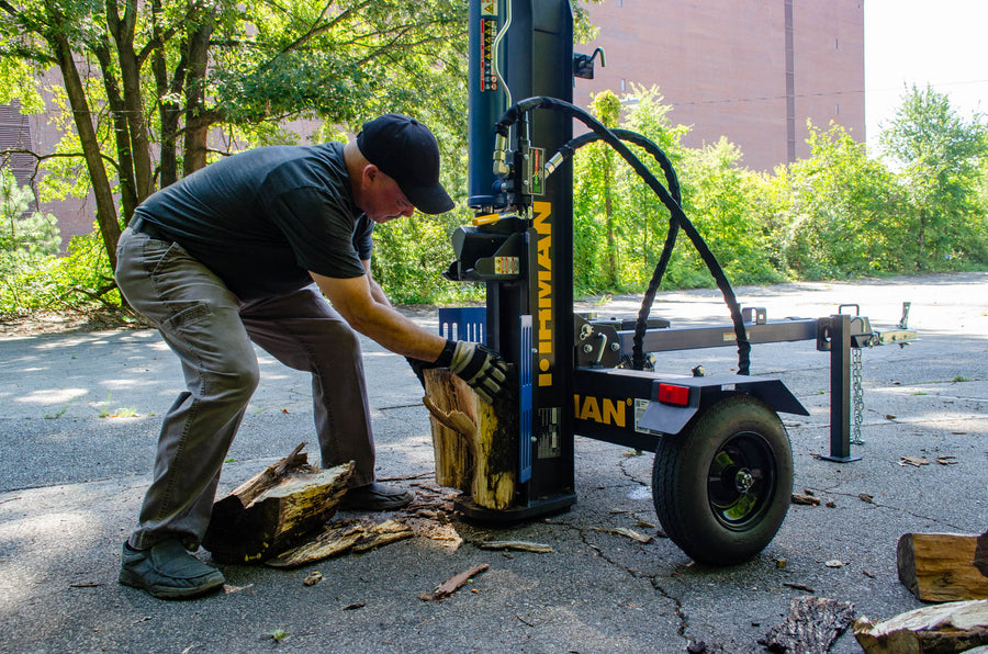 A man uses a FIRMAN Power Equipment GS2201, 22-Ton Log Splitter to split a wood log outdoors.