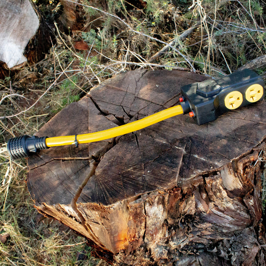 A yellow and black FIRMAN Power Equipment Heavy Duty L14-30P to (4) 5-20R Short Power Cord With Attachment Clips rests on a large tree stump in an outdoor setting.