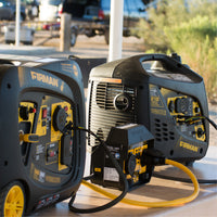 Two FIRMAN Power Equipment 50A Portable Generator Parallel Kits connect inverter generators on an outdoor table, with a parked vehicle visible in the background.