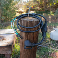 An outdoor wooden post with a FIRMAN Power Equipment 50A Parallel Cord Kit and a large electrical plug coiled around it.