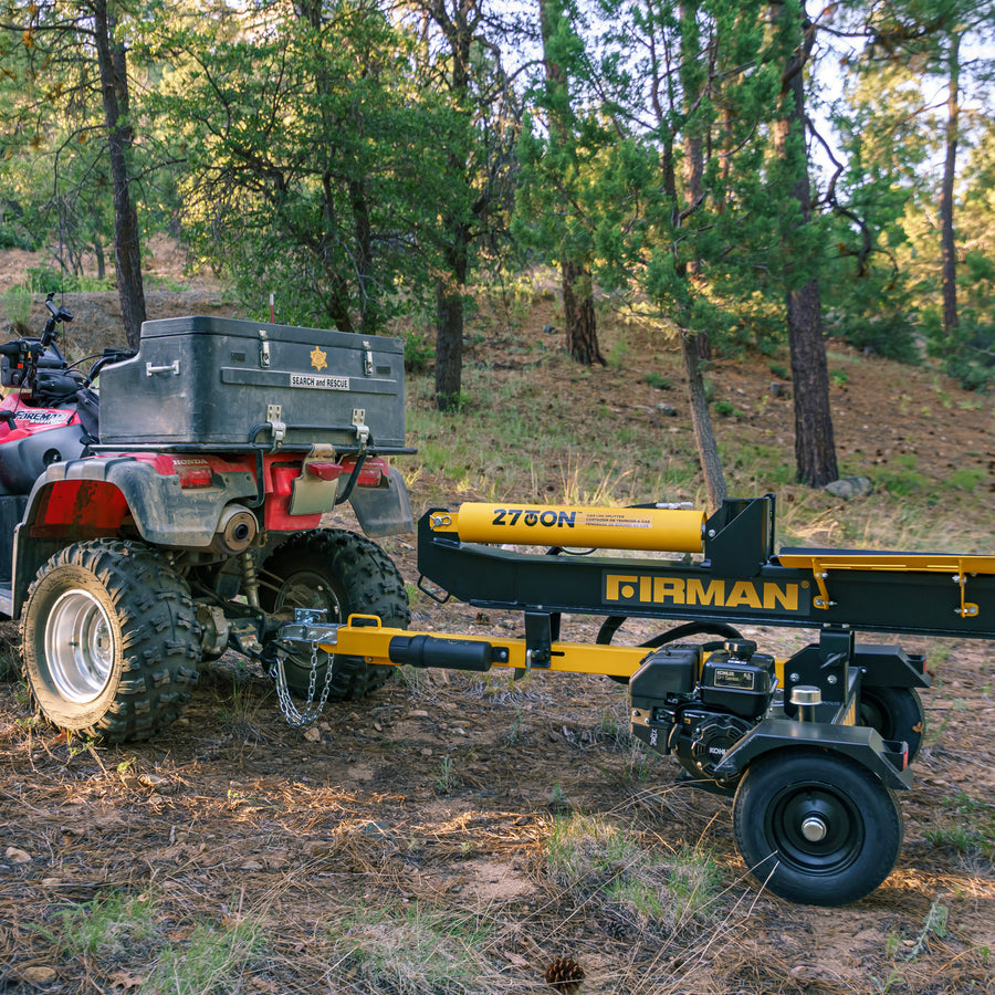 An ATV towing a yellow and black FIRMAN Power Equipment 27-Ton Log Splitter on a trailer through a forested area.