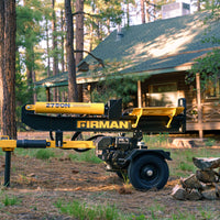 A 27-ton Log Splitter from FIRMAN Power Equipment, featuring a powerful 196 CC KOHLER Engine and colored in yellow, is positioned in front of a rustic cabin amidst a forest setting, with a small stack of split logs nearby.