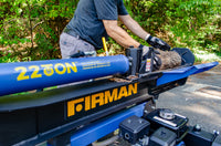 Man operating a FIRMAN Power Equipment 22-Ton Log Splitter to cut a large log outdoors under sunlight.