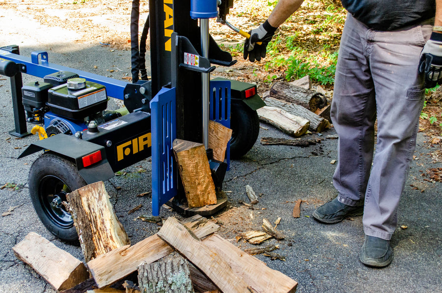 A person using a FIRMAN Power Equipment GS2201, 22-ton log splitter to split wood logs on a sunny day.