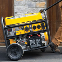 A person moves a yellow FIRMAN Power Equipment Gas Portable Generator 10000W Remote Start 120/240V with CO Alert on wheels outdoors near a stone and wood wall.