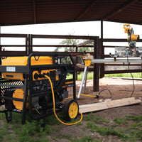 A FIRMAN Power Equipment gas portable generator 15000W electric start 120/240V with CO Alert and a table saw set up under a metal shelter on a construction site with dirt ground.
