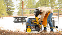 Lifestyle Image: Generator Model T07571 outdoors in the snow, connected to a propane tank, A man is using power tools that are connect to a power cord and generator.