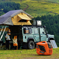 A Land Rover with a rooftop tent is set up for camping on grassy terrain, with gear scattered around and an orange FIRMAN Power Equipment Gas Inverter Portable Generator 2000/1600W Recoil Start in the foreground.