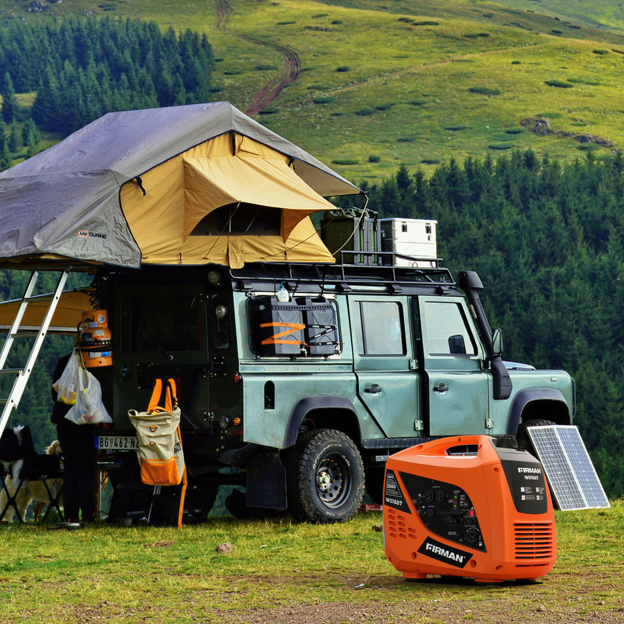 A Land Rover with a rooftop tent is set up for camping on grassy terrain, with gear scattered around and an orange FIRMAN Power Equipment Gas Inverter Portable Generator 2000/1600W Recoil Start in the foreground.