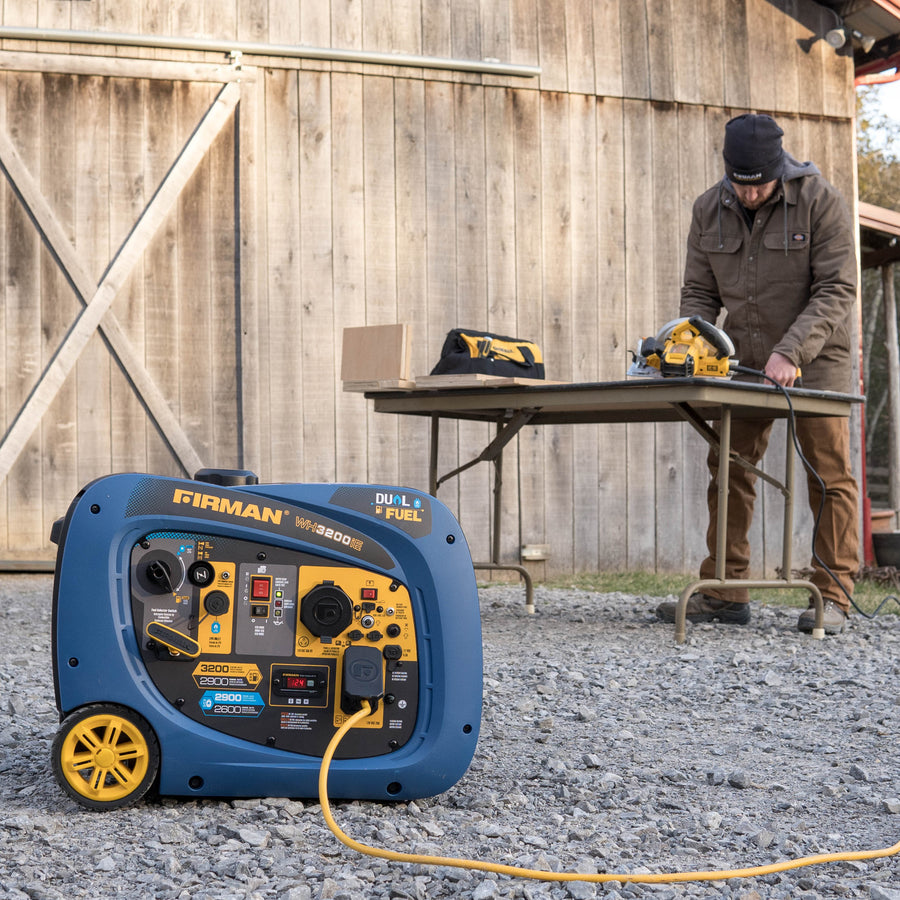 A FIRMAN Power Equipment Dual Fuel Inverter Portable Generator 3200W Electric Start is running on gravel, powering tools on a table as someone works outside a wooden building.