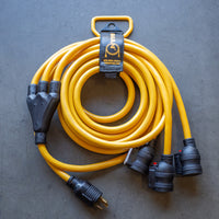 A yellow, FIRMAN Power Equipment 25' Heavy Duty L5-30P to (3) 5-20R power cord neatly coiled on a gray surface, featuring a triple outlet at one end and a standard plug at the other.