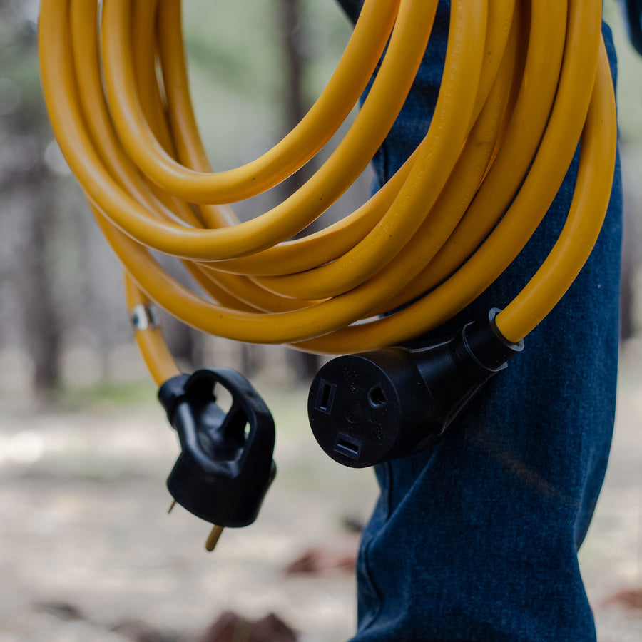 A person holding a FIRMAN Power Equipment 25' Heavy Duty TT-30P to TT-30R Power Cord With Storage Strap.
