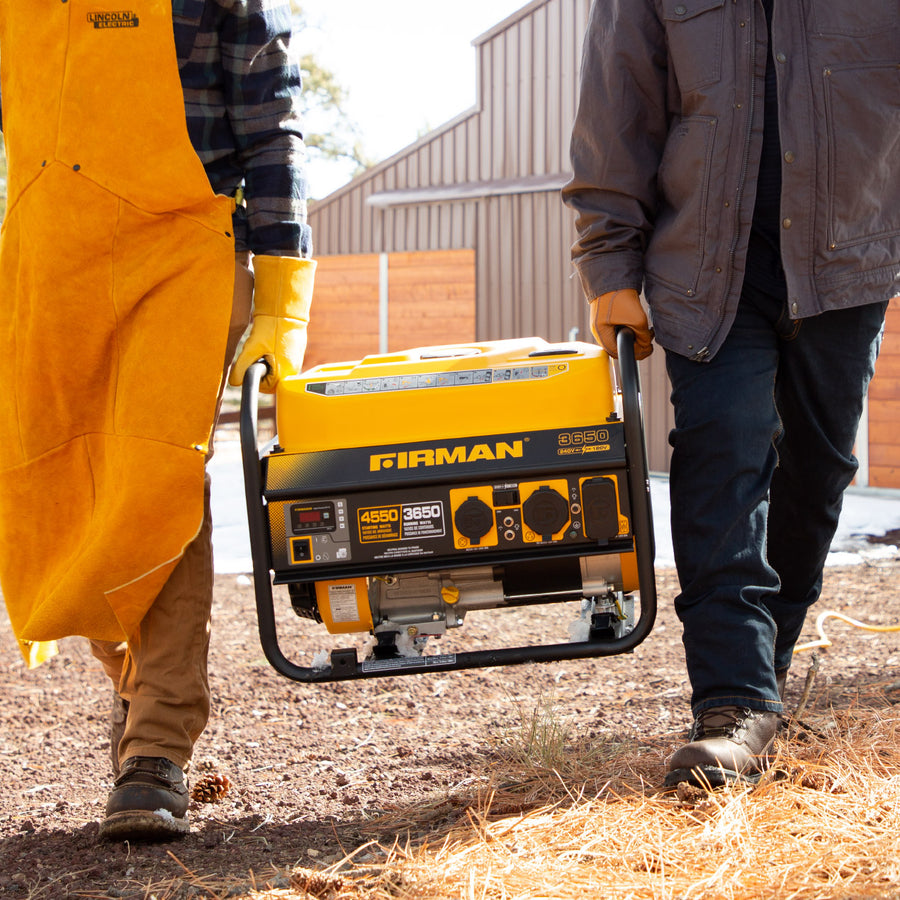 Two people outdoors carrying a yellow FIRMAN Power Equipment Gas Portable Generator 4550W Recoil Start 120/240V. One person is in a yellow overall and the other in a dark jacket.