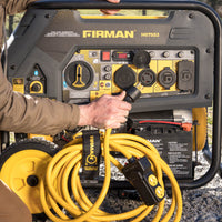 A person connects a yellow power cable to a FIRMAN Power Equipment Dual Fuel Portable Generator 9400W Electric Start 120/240V with CO Alert.