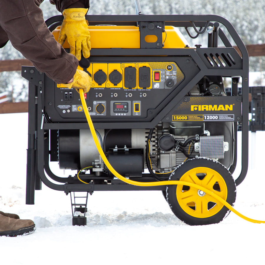 A person operates a large FIRMAN Power Equipment Gas Portable Generator 15000W Electric Start 120/240V power generator outdoors in the snow, connecting a yellow cable.