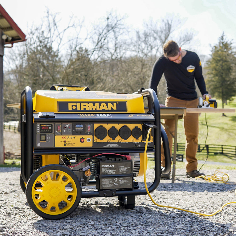 A person using a FIRMAN Power Equipment Gas Portable Generator 11400W Remote Start 120/240V with CO alert outdoors near a work table.