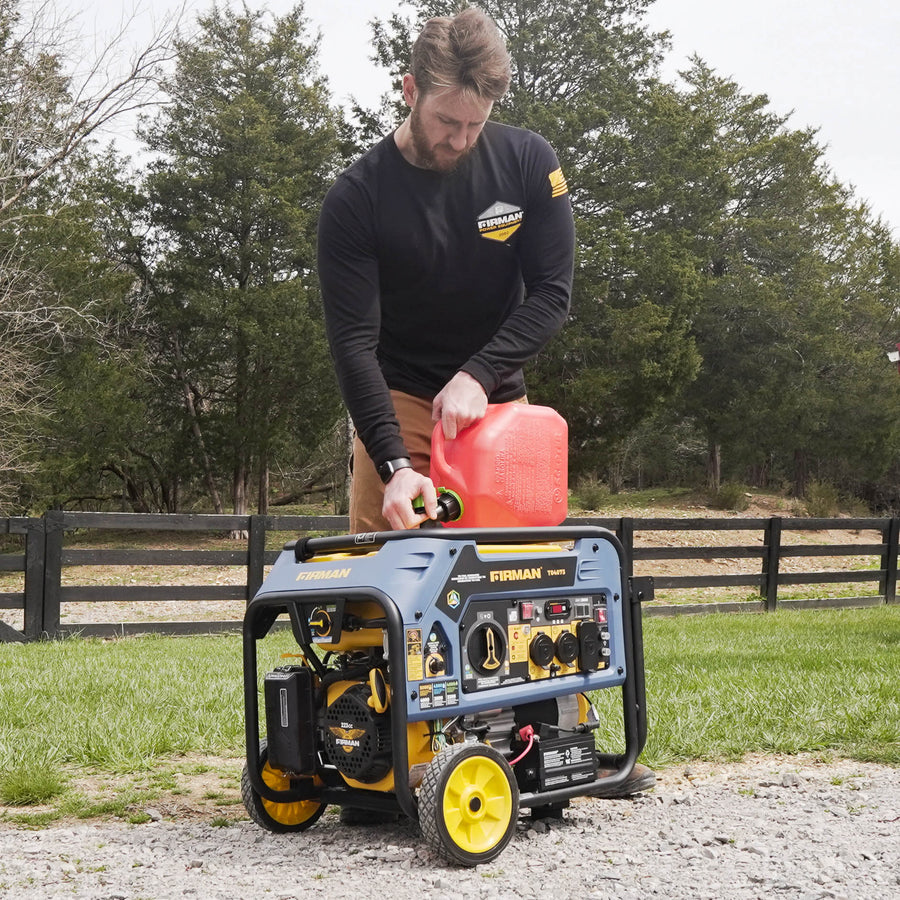 Man refueling a FIRMAN Power Equipment Tri Fuel Portable Generator 4000W Electric Start 120/240V with CO ALERT outdoors next to a fence-lined field.