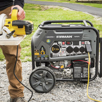 A person holding a circular saw and a FIRMAN Power Equipment Tri Fuel Portable Generator 9400W Electric Start 120/240V with CO Alert.