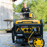 A man uses a table saw powered by a fuel-efficient FIRMAN Power Equipment Inverter Open Frame Portable Generator 4500W Remote Start with CO Alert outdoors, with a barn in the background.