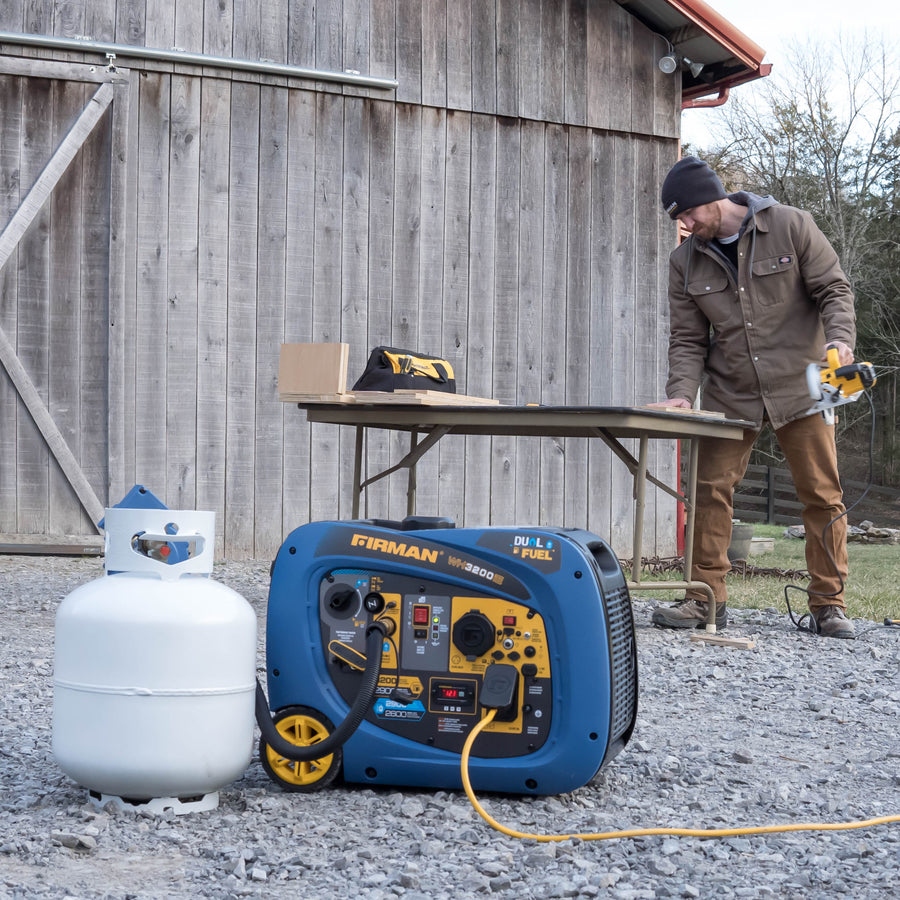 A man using a circular saw at a work table outside a wooden barn, with a blue FIRMAN Power Equipment Refurbished Dual Fuel Inverter 3200W Electric Start generator connected to a propane tank nearby.