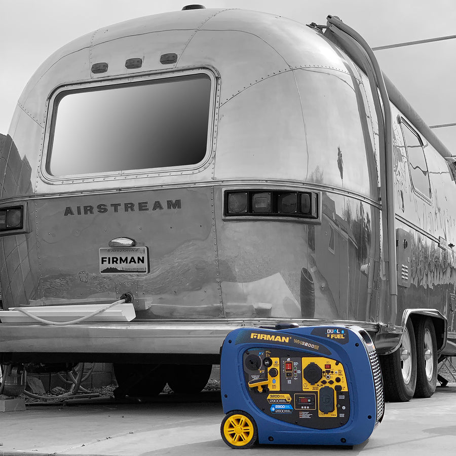 A portable FIRMAN Power Equipment Dual Fuel Inverter Portable Generator 3200W Electric Start in front of a shiny airstream travel trailer parked outdoors.