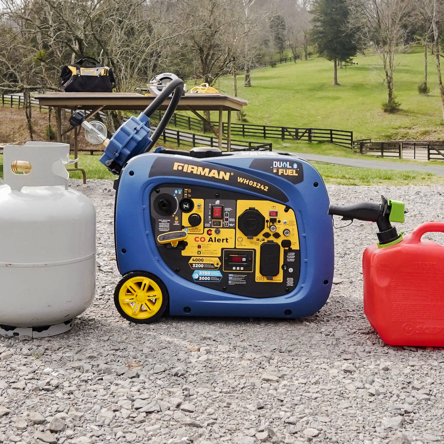 FIRMAN Power Equipment Dual Fuel Inverter Portable Generator 4000W Electric Start with CO ALERT on gravel with a propane tank and gas can nearby, set against a grassy field and trees.